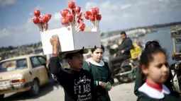 Haitham Khzaiq (16), anak Palestina yang berhenti sekolah enam bulan lalu menjual apel manis dan menghasilkan sekitar 20 Shekels ($ 5.1) per hari di Pelabuhan Kota Gaza, (17/3). Khzaiq mempunyai mimpi menjadi Insinyur arsitek. (REUTERS/Mohammed Salem)