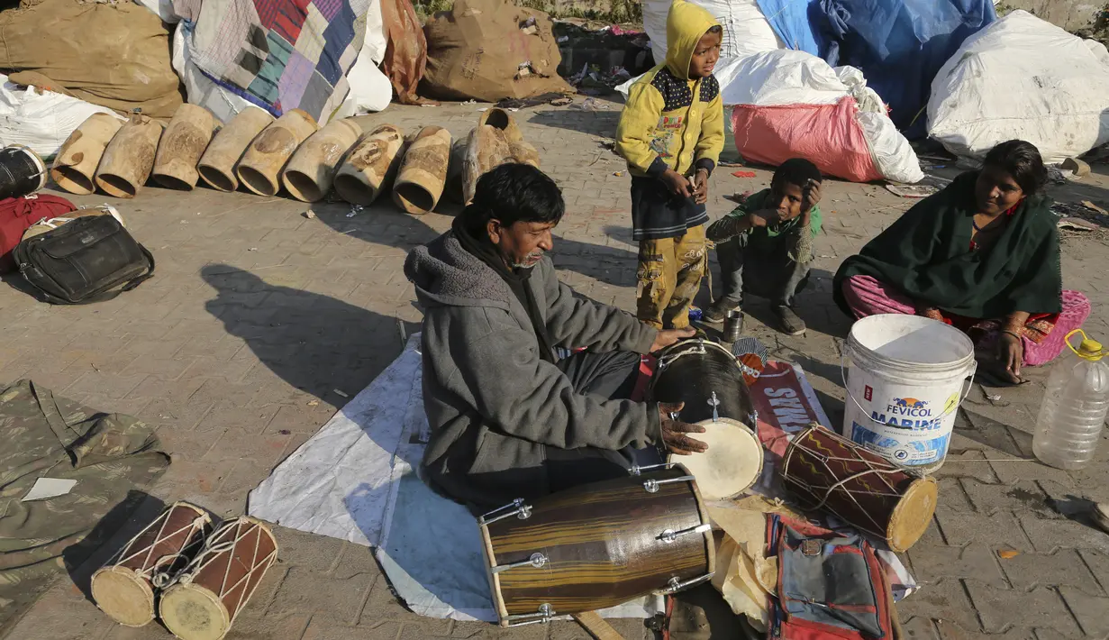 Seorang pria mencoba genderang  tradisional yang dibuatnya di daerah kumuh di Jammu, India (19/1/2021). Drum tradisional ini digunakan terutama saat pernikahan dan prosesi keagamaan. (AP Photo / Channi Anand)