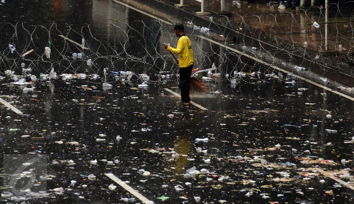 Petugas kebersihan menyapu jalan Medan Merdeka Barat yang dipenuhi sampah usai perayaan hari Buruh Internasional, Jakarta, Senin (5/1). Ribuan massa buruh ikut dalam perayaan Hari Buruh Internasional 2017. (Liputan6.com/Helmi Fithriansyah)