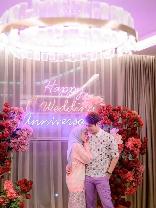 Lesti bergaya ala cewek kue di momen spesialnya ini. Dia memadukan cardigan pink, celana bermotif, dan hijab warna abu-abu. (Instagram/askar_photography/lestykejora).