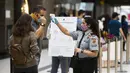 Petugas keamanan yang mengenakan masker memeriksa suhu tubuh seorang pelanggan di luar gerai Apple, Toronto, Kanada, 6 Oktober 2020. Hingga Selasa (6/10/2020) sore waktu setempat, Kanada melaporkan 170.945 kasus COVID-19 termasuk 9.527 kematian. (Xinhua/Zou Zheng)
