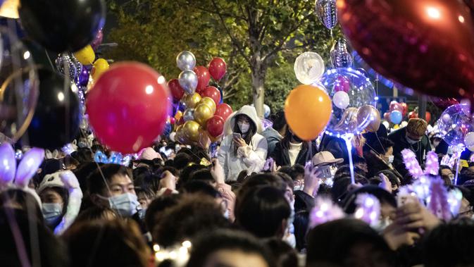 Orang-orang menghadiri  hitung mundur di Wuhan, provinsi Hubei, China (1/1/2021). Banyak yang membawa balon untuk dilepaskan ketika jam menunjukkan pukul 12 pagi. (AFP/Noel Celis)