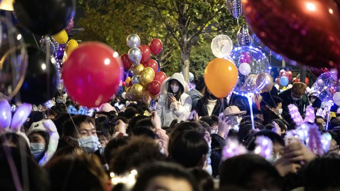 Orang-orang menghadiri hitung mundur di Wuhan, provinsi Hubei, China (1/1/2021). Banyak yang membawa balon untuk dilepaskan ketika jam menunjukkan pukul 12 pagi. (AFP/Noel Celis)