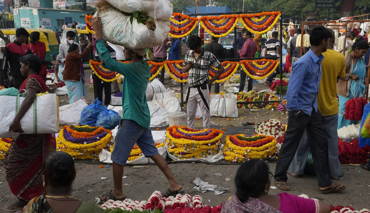 Pembeli berjalan melewati pedagang yang menjual bunga di pasar grosir di Bengaluru, India, Rabu (13/4/2022). Orang-orang telah kembali beraktivitas normal setelah pihak berwenang mencabut pembatasan COVID-19 termasuk mengenakan masker wajah di tempat-tempat umum. (AP Photo/Aijaz Rahi)