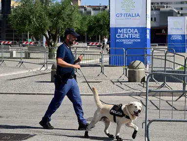 Seorang petugas polisi berjalan dengan anjing pelacak di pintu masuk Pusat Media Konferensi Tingkat Tinggi (KTT) G7 di Bari, Apulia, Italia pada tanggal 12 Juni 2024. (Tiziana FABI/AFP)
