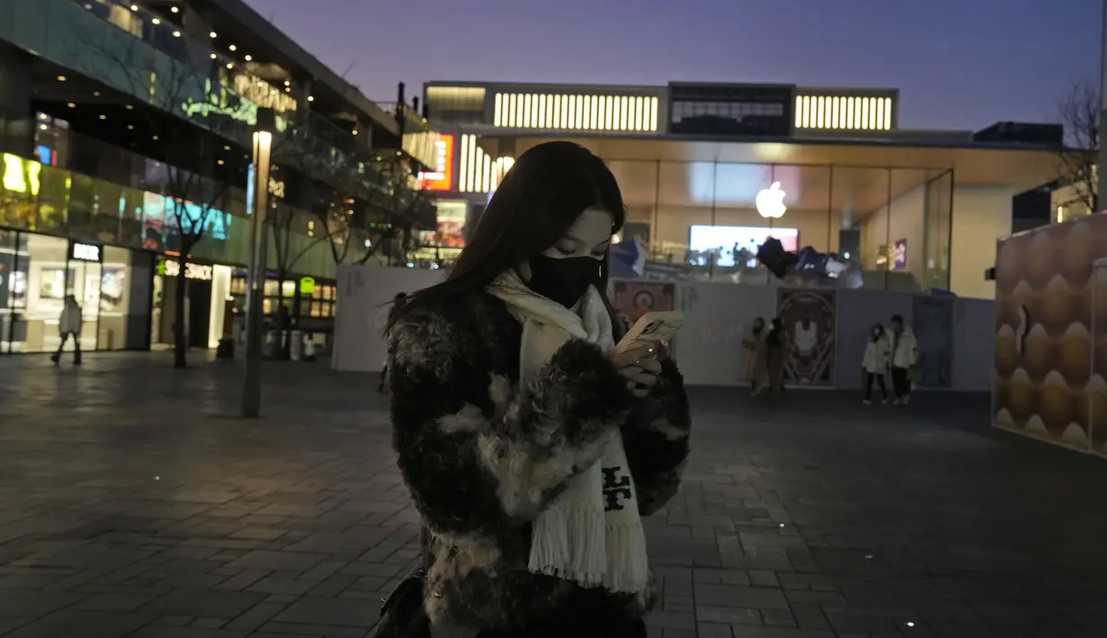 <p>Seorang wanita memakai masker berjalan di sepanjang mal di Beijing, Rabu (28/12/2022). China mengatakan akan melanjutkan penerbitan paspor untuk pariwisata dalam langkah besar lainnya dari kontrol anti-virus yang mengisolasi negara itu selama hampir tiga tahun, menyiapkan potensi banjir orang China yang pergi ke luar negeri untuk liburan Tahun Baru Imlek bulan depan. (AP Photo/Ng Han Guan)</p>