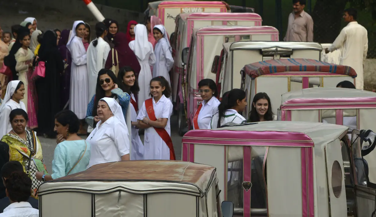 Para wanita dan biarawati Pakistan berkumpul di sekitar becak merah muda saat aksi untuk meningkatkan kesadaran wanita, menunjukkan kesetaraan dan pemberdayaan perempuan di Lahore, (14/10). (AFP PHOTO / Arif Ali)