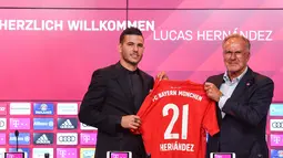 Bek baru Bayern Munchen, Lucas Hernandez berpose bersama CEO Bayern Munchen, Karl-Heinz Rummenigge sambil memegang jersey saat diperkenalkan secara resmi di Allianz Arena, Senin (8/7/2019). Pemain 23 tahun ini diikat kontrak selama lima tahun atau hingga 2024 oleh Bayern. (Christof STACHE/AFP)