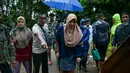 Seorang wanita berjalan dengan bantuan alat bantu jalan setelah dievakuasi dari daerah di mana jalannya saat ini terendam banjir di Sementeh, dekat Lanchang di negara bagian Pahang Malaysia (6/1/2021). Warga dievakuasi ke aula Kampung Jara dekat Kuala Sentul. (AFP/Mohd Rasfan)