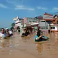 Sejumlah warga berjalan di genangan banjir yang merendam kota Bandung, Jawa Barat, Minggu (13/3). Kawasan Bandung Selatan kembali dilanda banjir akibat luapan Sungai Citarum dan membuat lebih dari 3000 jiwa mengungsi. (Timur Matahari/AFP)