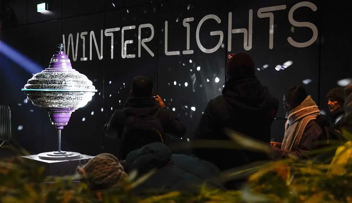 Orang-orang memotret "Fragmented Appearances" karya Gertjan Adema, sebagai bagian dari festival Winter Lights di Canary Wharf, London, Rabu (18/1/2023). Festival Winter Lights kembali ke Canary Wharf untuk pertama kalinya sejak 2020. (AP Photo/Alberto Pezzali)