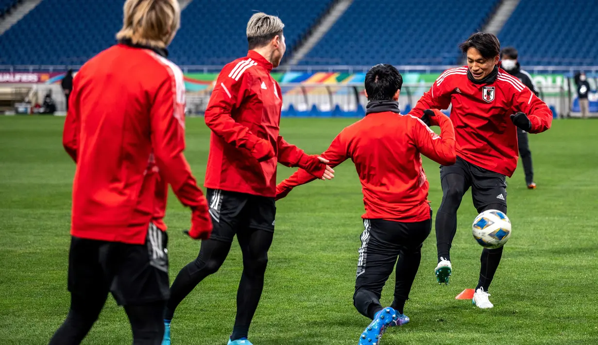 Para pemain Jepang melakukan pemanasan dalam sesi latihan di Stadion Saitama di Saitama (31/1/2022). Jepang untuk sementara berada di urutan kedua dan terpaut 4 poin dari Arab Saudi yang memimpin klasemen Grup B dengan raihan 19 poin dari 7 laga. (AFP/Philip Fong)