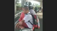 Bocah SD duduk bersila saat diboceng motor. (capture/istimewa)