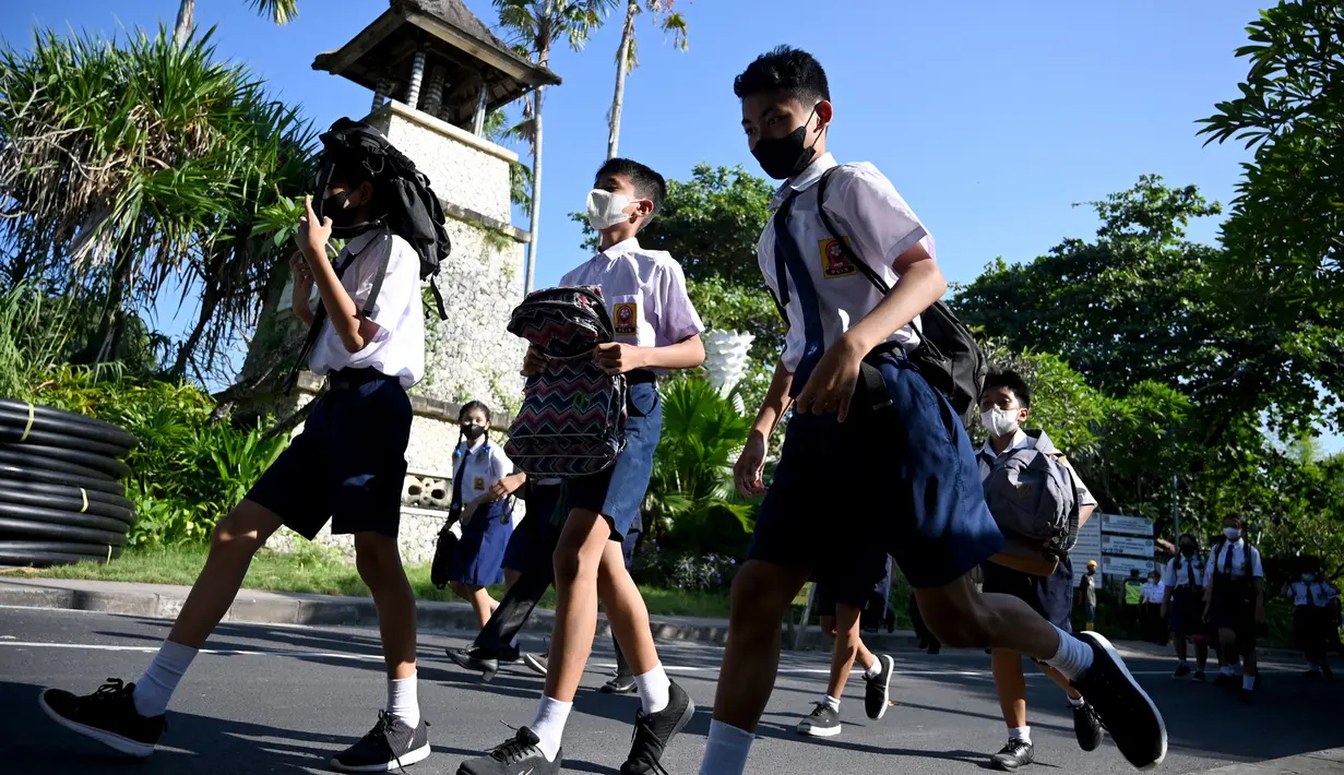 Anak-anak sekolah menggunakan tas mereka untuk melindungi diri saat latihan gempa dan tsunami di Tanjung Benoa, Kabupaten Badung, Bali, 24 Mei 2022. (SONY TUMBELAKA/AFP)
