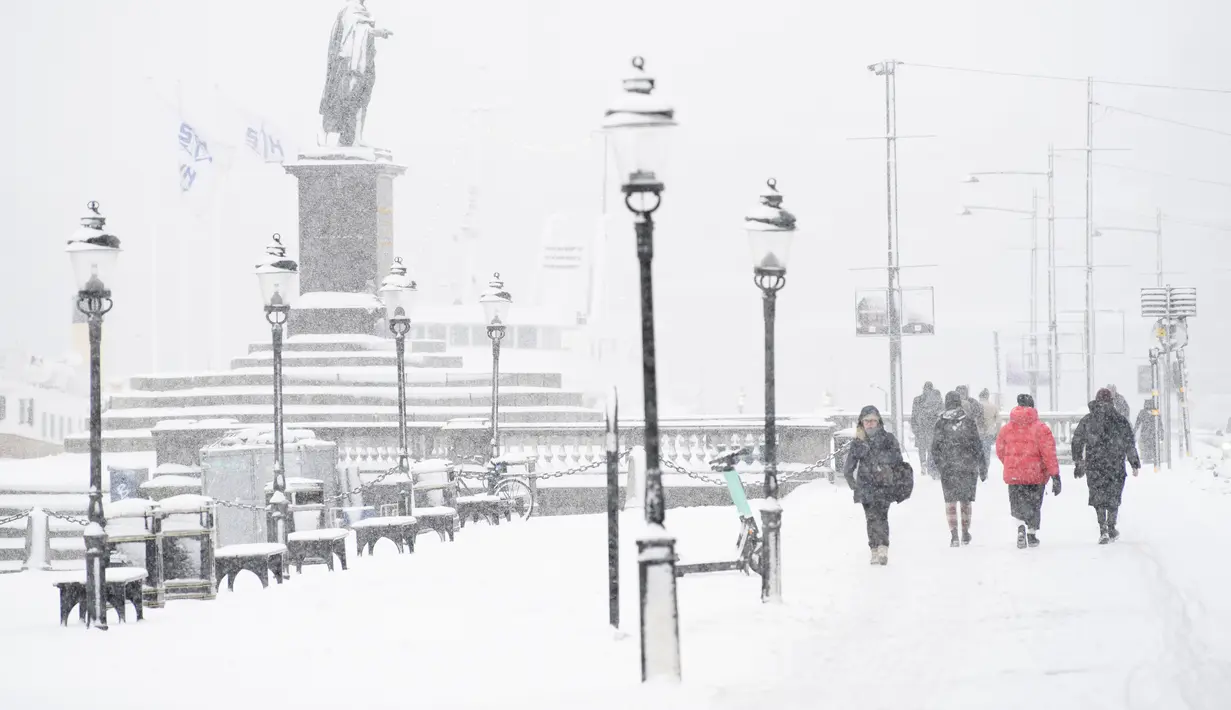 Orang-orang berjalan saat salju turun di Skeppsbron di Stockholm, Swedia (28/1/2021). Badan cuaca nasional Swedia, SMHI, telah mengeluarkan peringatan untuk salju lebat di Stockholm dan Uppsala. (Henrik Montgomery/TT via AP)