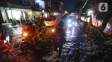 Pengendara bermotor melewati genangan air di kawasan Jalan Dr. Setiabudi, Pamulang, Tangerang Selatan, Rabu (6/12/2023). (merdeka.com/Arie Basuki)