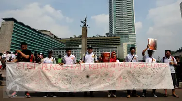 Sekelompok warga membentangkan Petisi Penolakan Kenaikan Tarif Dasar Listrik di kawasan Bundaran HI, Jakarta, Minggu (7/5). Mereka meminta pihak berwenang mengkaji kembali kebijakan kenaikan tarif dasar listrik. (Liputan6.com/Helmi Fithriansyah)