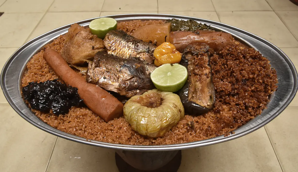 Thiebou dieune yang terbuat dari nasi, ikan, dan berbagai sayuran difoto di sebuah rumah di Parcelles Assainies di Dakar pada 15 Desember 2021. Namun ada aturan khusus saat memakannya, yaitu tak boleh mengangkat salah satu kaki saat makan, ataupun menjatuhkan sebutir nasi pun. (SEYLLOU/AFP)
