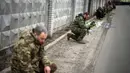 Tentara Ukraina berlutut menunggu peti mati Oleksandr Maksymenko (38) lewat saat pemakamannya di kampung halamannya di Kniazhychi, sebelah timur Kyiv, Ukraina, 13 Februari 2023. Oleksandr Maksymenko, seorang warga sipil yang menjadi sukarelawan di angkatan bersenjata Ukraina, tewas dalam pertempuran di daerah Bakhmut. (AP Photo/Emilio Morenatti)