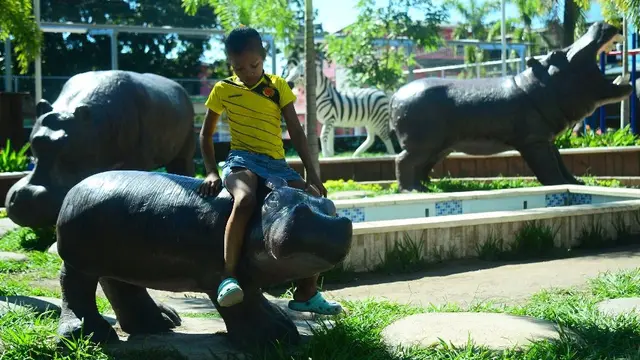 Seorang anak laki-laki duduk di patung kuda nil di lingkungan Jorge Tulio Garces di Doradal, Kolombia, dekat taman hiburan Hacienda Napoles.