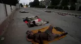Para pekerja tidur di pinggir jalan pada pagi hari yang panas di awal musim panas di Karachi, Pakistan, Rabu, 29 Mei 2024. (AP Photo/Fareed Khan)