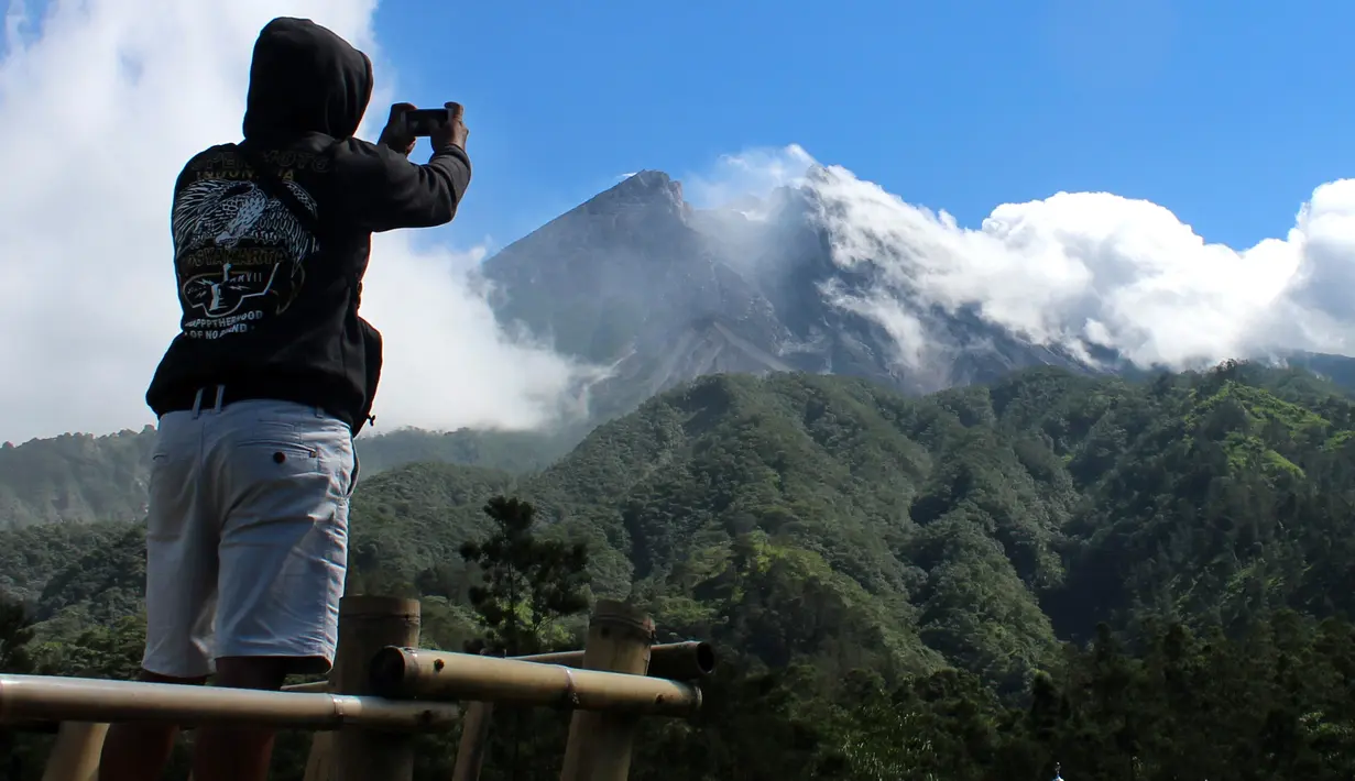 Seorang pria mengambil gambar Gunung Merapi di Cangkringan, Indonesia, Selasa, (22/5). Pihak berwenang meningkatkan kewaspadaan terhadap Gunung Merapi yang bergejolak di pulau Jawa. (AP Photo/A.K. Hendratmo)