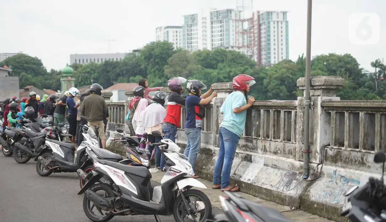 Pengendara sepeda motor mengamati banjir yang menggenangi kawasan Rawajati dari atas flyover di Jakarta Timur, Rabu (1/1/2020). Banjir yang berasal dari luapan Sungai Ciliwung itu menjadi daya tarik tersendiri bagi sebagian pemotor yang melintasi di flyover tersebut. (Liputan6.com/Immanuel Antonius)