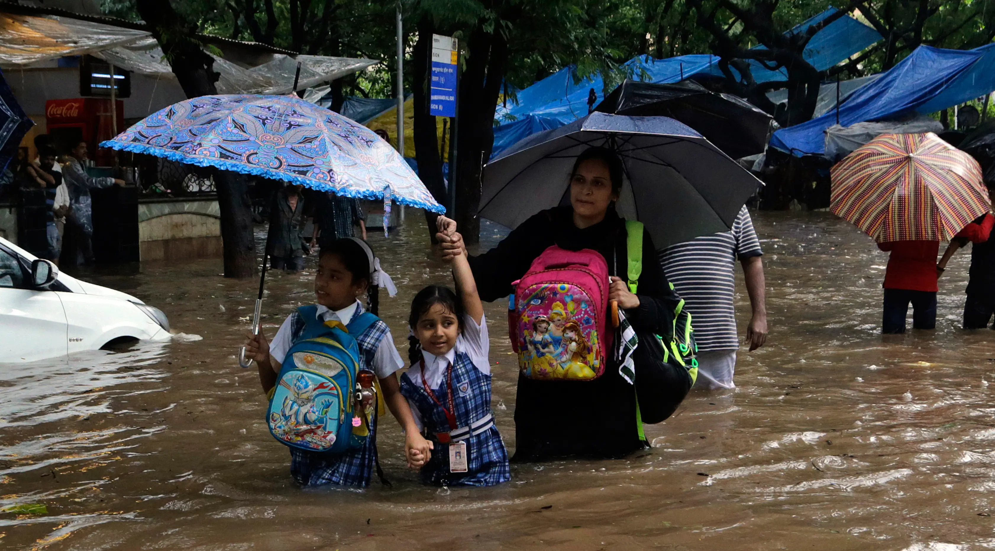 Dua anak sekolah menerobos jalanan yang terendam banjir akibat hujan lebat mengguyur kota Mumbai di India, Selasa (29/8). Air hujan juga membanjiri King Edward Memorial Hospital di Mumbai Tengah. (AP Photo/Rajanish Kakade)