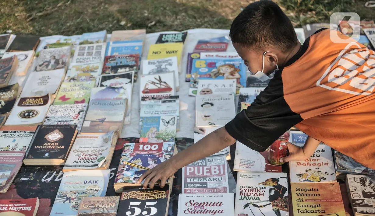 Seorang anak memilih buku saat kehadiran Perpustakaan Keliling di kawasan Kampung Melayu, Jakarta, Minggu (16/8/2020). Kegiatan sosial ini menghadirkan latihan tari, donasi pakaian layak, makanan, serta masker. (merdeka.com/Iqbal S. Nugroho)