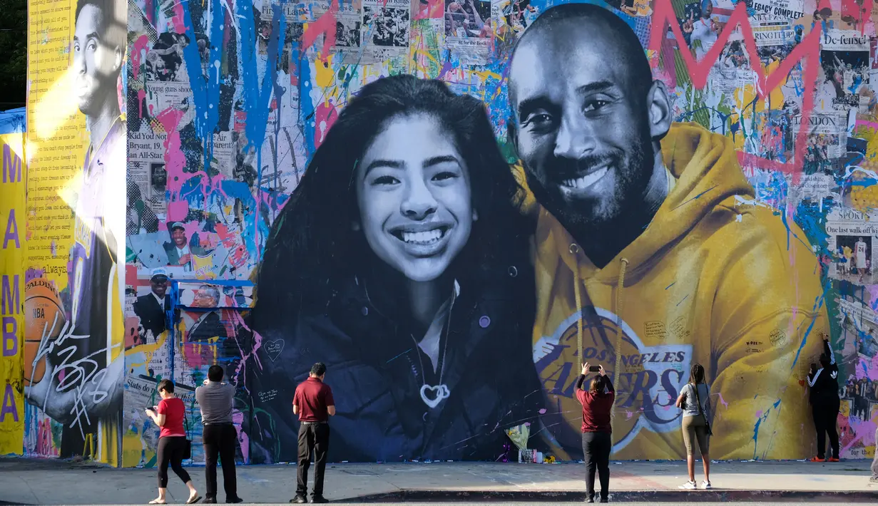 Orang-orang mengabadikan mural Kobe Bryant dan Putrinya Gigi buatan seniman Prancis Mr. Brainwash di Los Angeles (31/1/2020). Bryant memenangkan lima gelar juara NBA dan peraih medali emas Olimpiade dua kali. (AFP/Chris Delmas)