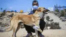 Relawan Palestina di Sula Society for Animal Care Saeed al-Err berfoto bersama Billy, seekor anjing yang diamputasi yang menjalani rehabilitasi di asosiasi penampungan  di Kota Gaza (9/9/2020). (AFP Photo/Mohammed Abed)
