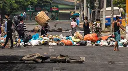 Seorang pengunjuk rasa membuang sampah di jalan saat demonstrasi menentang kudeta militer di kota Thaketa Yangon, Myanmar, Selasa (30/3/2021). "Serangan sampah" menjadi taktik baru untuk melawan junta militer saat jumlah korban tewas dalam demo anti-kudeta mencapai lebih dari 500. (HO/FACEBOOK/AFP)