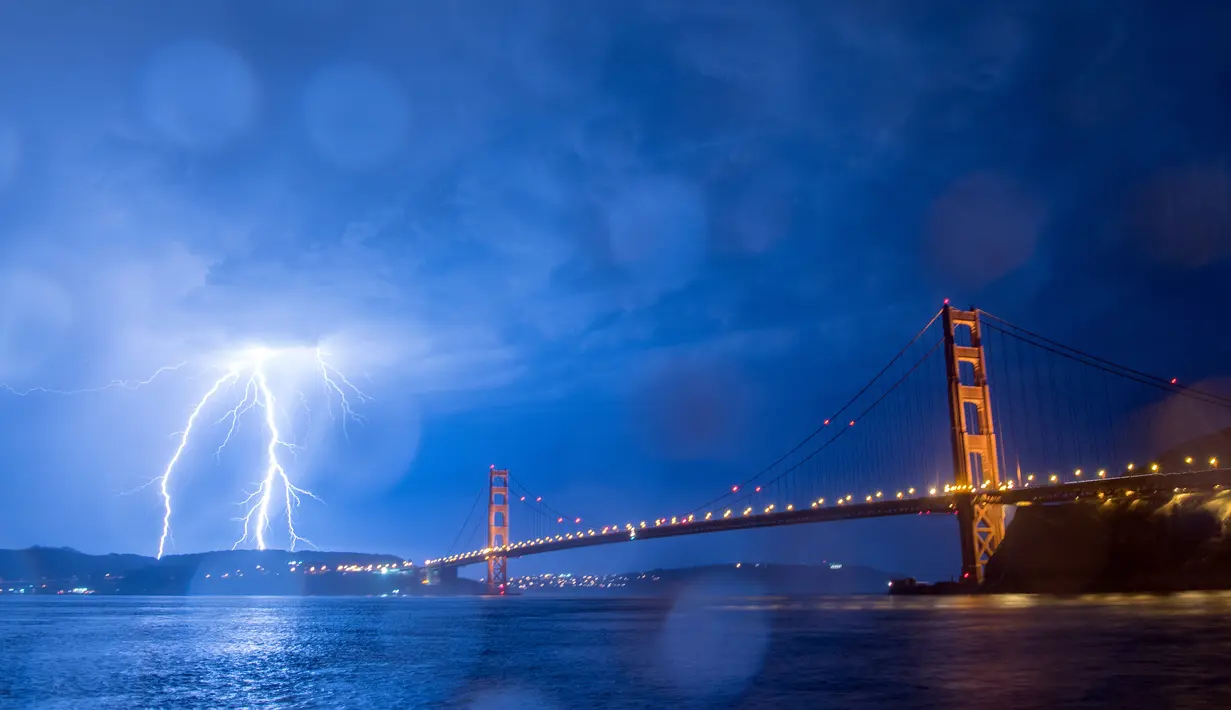 Kilatan petir hiasi jembatan Golden Gate di San Francisco, California, AS (11/9). Petir merupakan Gejala alam yang biasanya muncul pada musim hujan di saat langit memunculkan kilatan cahaya sesaat yang menyilaukan. (AFP Photo/Josh Edelson)