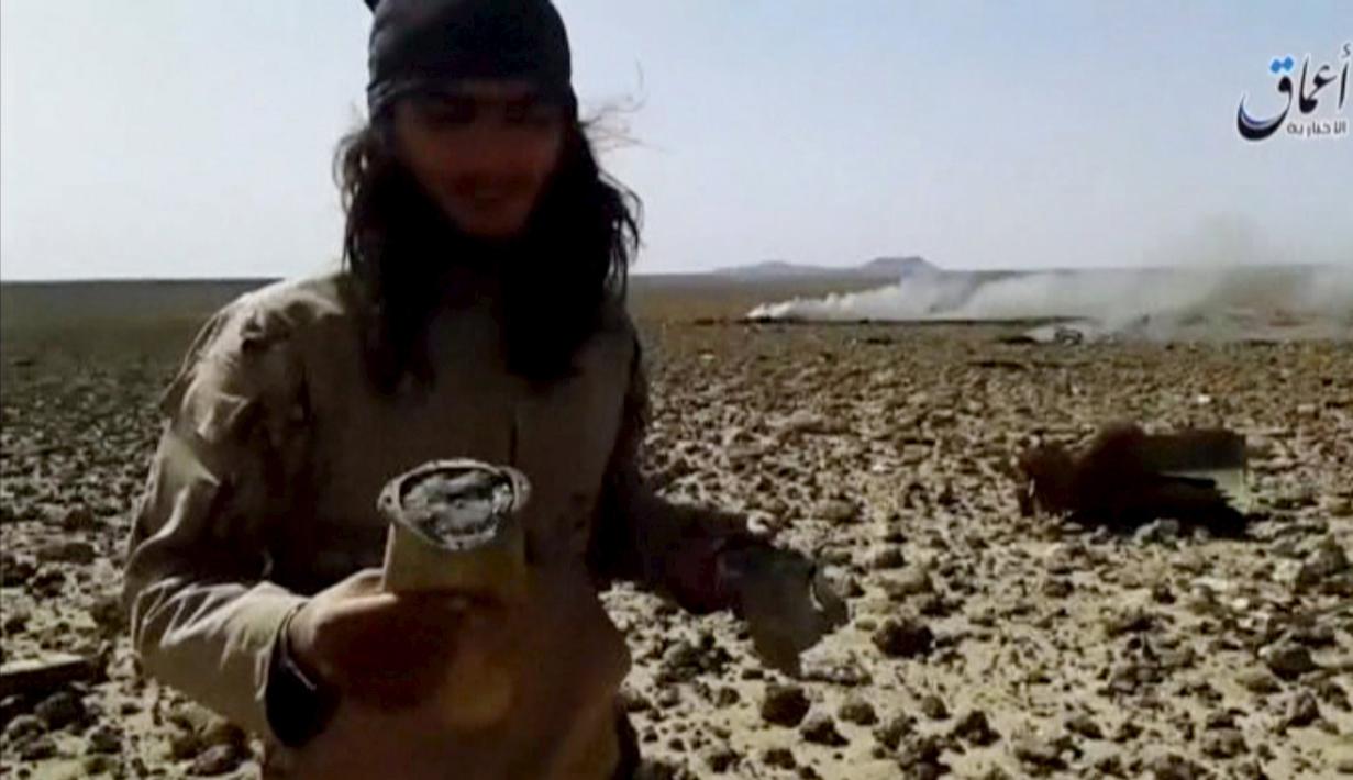 Seorang pria berpose didekat bangkai pesawat yang jatuh dan terbakar di sebelah tenggara Damaskus, Jumat, (22/4). ISIS juga mengaku telah menangkap pilot pesawat itu setelah terjun dengan parasut. (Reuters)