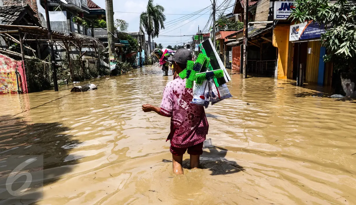 Pedagang alat kebersihan menerobos banjir di kompleks Pondok Gede Permai, Jatiasih, Bekasi, Jumat (22/4). Mereka menjajakan dagangannya berupa alat kebersihan ketika banjir di  kawasan tersebut mulai surut. (Liputan6.com/Fery Pradolo)