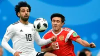 Penyerang Mesir, Mohamed Salah berusaha mengontrol bola dari kawalan pemain Rusia, Yuri Zhirkov saat bertanding pada grup A Piala Dunia 2018 di stadion St. Petersburg di St. Petersburg, (19/6). (AP Photo / Martin Meissner)