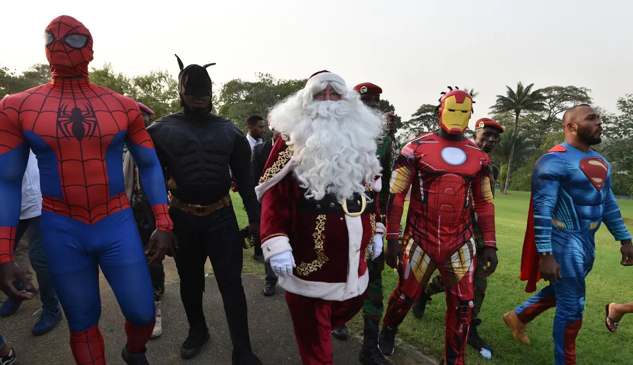 Sejumlah pria mengenakan kostum pahlawan super berjalan di istana kepresidenan di Pantai Gading (23/12). Mereka mengenakan kostum pahlawan super sambil membawa hadiah yang diberikan kepada anak-anak untuk perayaan natal. (AFP Photo/Sia Kambou)