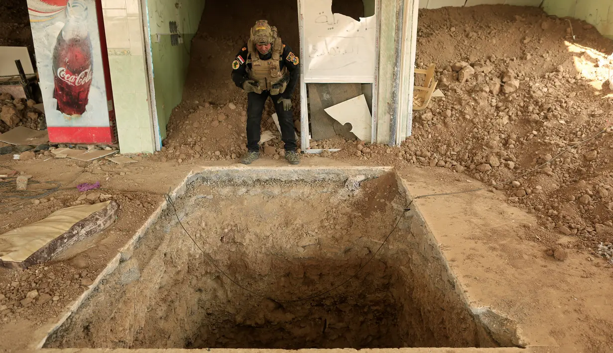 Seorang anggota pasukan khusus Irak berada di dekat sebuah pintu masuk terowongan yang digunakan oleh militan ISIS di dalam sebuah restoran di Bazwaya, timur Mosul, Irak (27/10). (REUTERS/Zohra Bensemra)