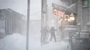 Pekerja menyekop salju dari pintu masuk restoran dan bar mereka saat badai salju melanda New York pada Senin, (1/2/2021). Badai salju menyebabkan timbunan salju setinggi satu kaki di sepanjang wilayah pesisir timur Amerika Serikat, termasuk Kota New York. (AP Photo/Wong Maye-E)