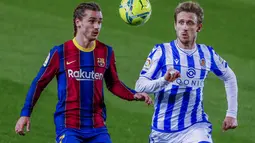 Penyerang Barcelona, Antoine Griezmann berebut bola dengan pemain Real Sociedad, Nacho Monreal pada pertandingan lanjutan La Liga Spanyol di stadion Camp Nou di Barcelona, Spanyol, Kamis (17/12/2020). Rambut kepang dua Griezmann juga dipamerkan dalam akun Instagram klub. (AP Photo/Joan Monfort)