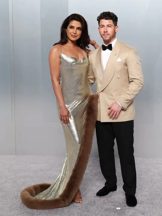 Pasangan power couple, Priyanka Chopra dan Nick Jonas, kembali membuktikan status mereka sebagai fashion icon. Priyanka mengenakan gaun metalik rancangan Stella McCartney dengan aksen fur yang dramatis, sementara Nick tampil sleek dalam tuxedo krem yang clean. Keduanya menghadirkan harmoni antara bold femininity dan refined masculinity.