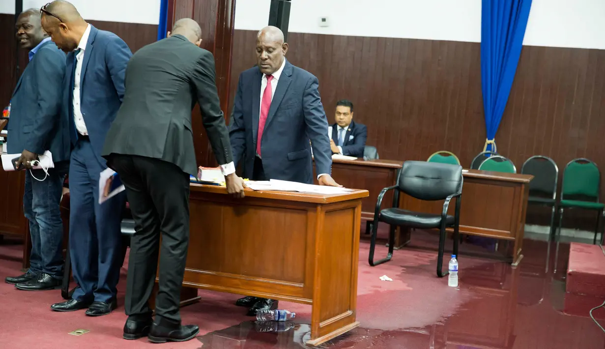 Anggota parlemen memindahkan meja menjauhi genangan air hujan yang membasahi lantai Gedung Parlemen Haiti, Port-au-Prince, Haiti, Rabu (21/8/2019). Saat kejadian, anggota parlemen sedang memperdebatkan proses impeachment Presiden Haiti Jovenel Moise atas tuduhan korupsi. (AP Photo/Dieu Nalio Chery)