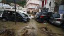 Mobil-mobil yang rusak terlihat di jalan yang banjir setelah hujan deras memicu tanah longsor yang meruntuhkan bangunan dan menyebabkan 12 orang hilang, di Casamicciola, di pulau Ischia, Italia selatan, Sabtu, 26 November 2022. (AP Photo/Salvatore Laporta)