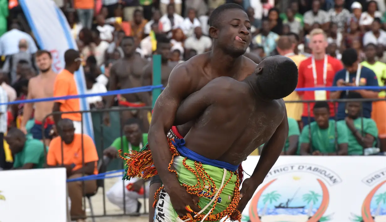 Konane Moussa dari Burkina Faso (kiri) bertarung dengan Mouhamadou Alimi dari Nigeria dalam pertarungan individu 65kg Pertarungan Gulat Tradisional selama Francophonie ke-8 di Treichville Sports Park di Abidjan pada 29 Juli 2017. (AFP Photo/Sia Kambou)