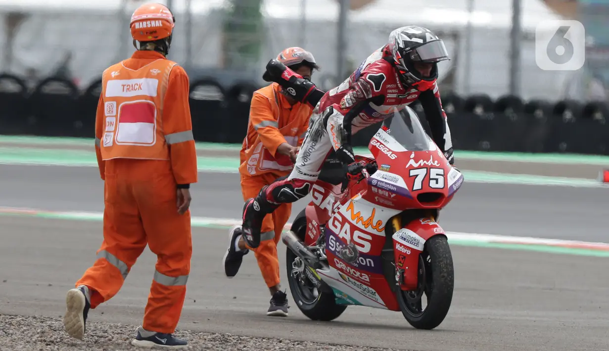 Marshal mendorong motor pembalap Albert Arenas saat kualifikasi Moto2, Pertamina Mandalika International Street Sirkuit, Lombok, Sabtu (19/3/2022). Marshal bertugas sesuai tupoksi ada yang di sirkuit, garis start, tikungan tajam, maupun di pitlane. (Liputan6.com/Helmi Fithriansyah)