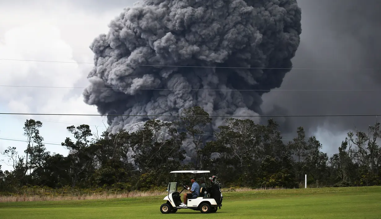 Kendaraan golf melintas saat kepulan asap abu vulkanik berembus dari puncak gunung Kiluaea di Big Island Hawaii (15/5). Kiluaea merupakan gunung berapi paling aktif di dunia. (AFP Photo/Mario Tama)