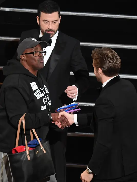 Seorang turis berjabat tangan dengan nominator Aktor Utama Terbaik Piala Oscar 2017, Ryan Gosling, selama Academy Awards ke-89, di California, Minggu (26/2). Presenter Jimmy Kimmel mengajak sejumlah turis masuk ke dalam Dolby Theatre. (Mark RALSTON/AFP)