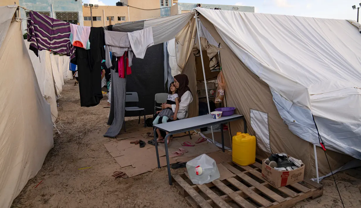 <p>Warga Palestina yang mengungsi akibat pemboman Israel di Jalur Gaza duduk di tenda kamp yang disediakan UNDP di Khan Younis, Kamis (19/10/2023). (AP Photo/Fatima Shbair)</p>