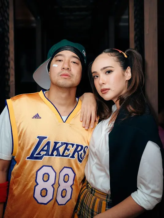 Pamela mengenakan kemeja fit body, rok kotak-kotak berwarna kuning, dan sweater di bahunya. [@pammybowie/@@makeupbycla]