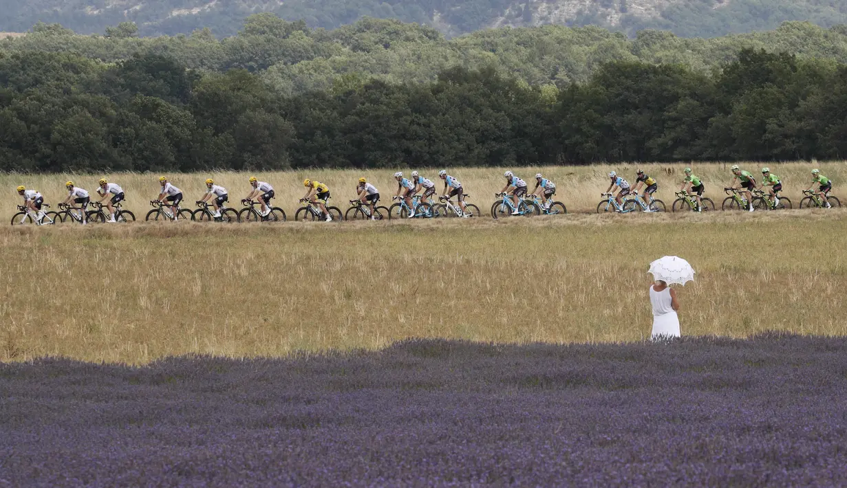 Seorang wanita dengan gaun dan payung putih menonton balapan Tour de France etape ke-19 dengan jarak tempuh 222,5 km dari Embrun menuju Salon-de-Provence, Prancis, (21/7/2017). (AP/Christophe Ena)